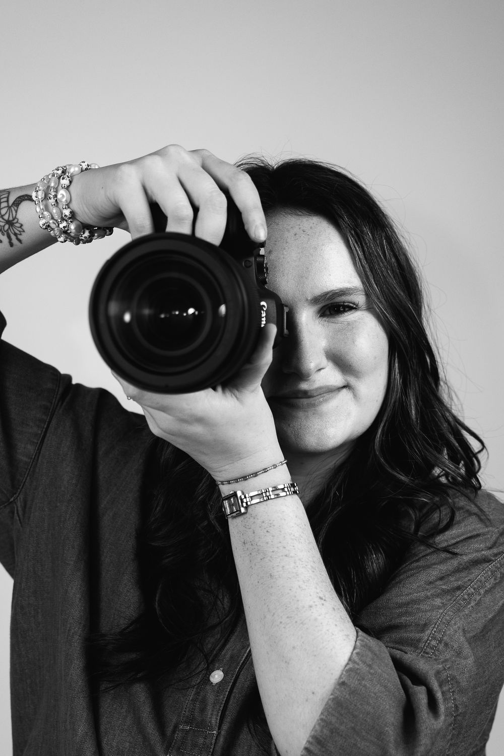 Black and white portrait of photographer holding professional camera lens.
