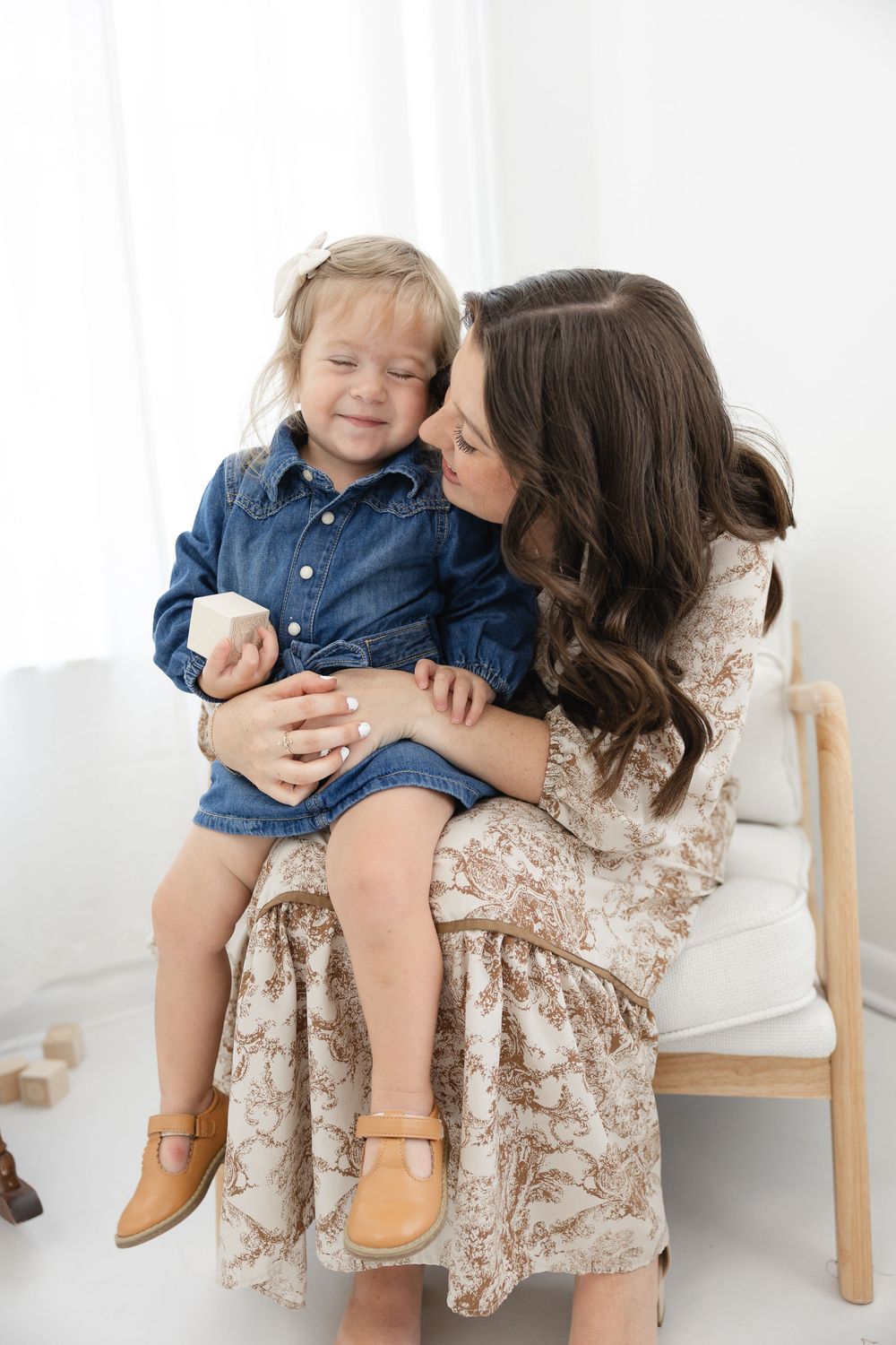 A sweet moment captured in a studio with a floral dress and denim outfit against a white backdrop.