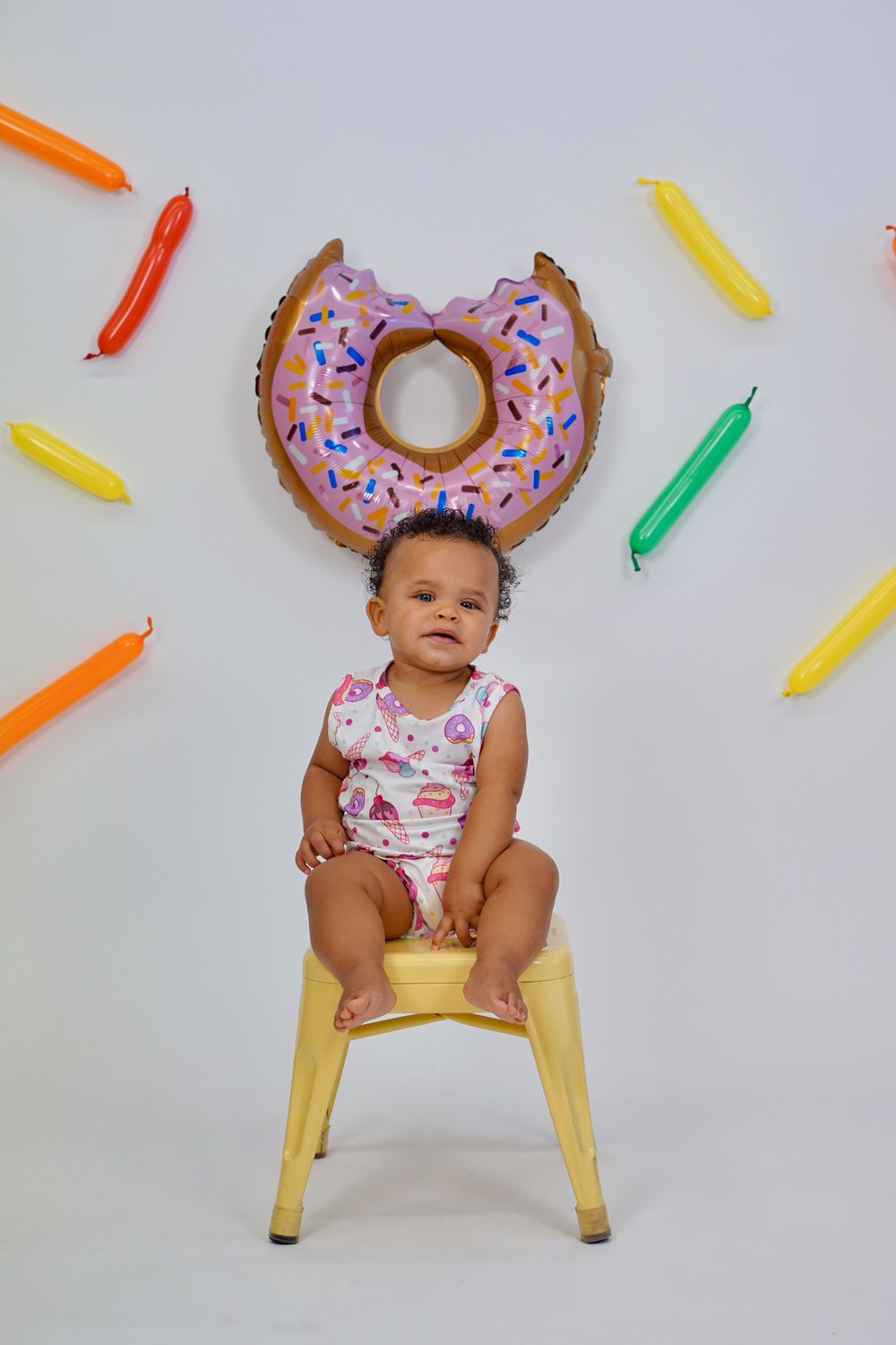 Colorful donut props and decorative crayons create a playful setting for a fun photo shoot against a white backdrop.