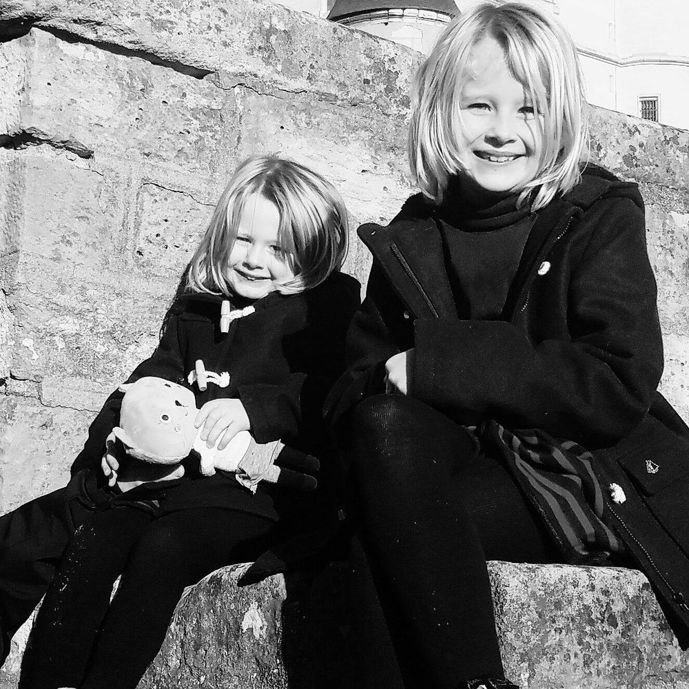 Black and white photo sequence showing playful interaction between two people against a textured stone wall.
