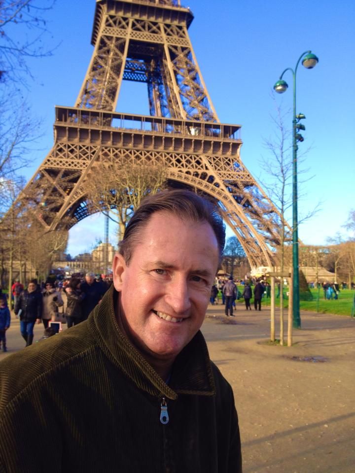 Tourist taking selfie photos in front of the iconic Eiffel Tower in Paris during daytime.