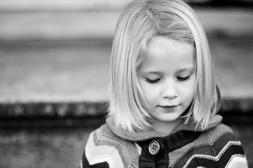 A series of black and white portrait photographs showing a child with blonde hair in different expressions and poses.