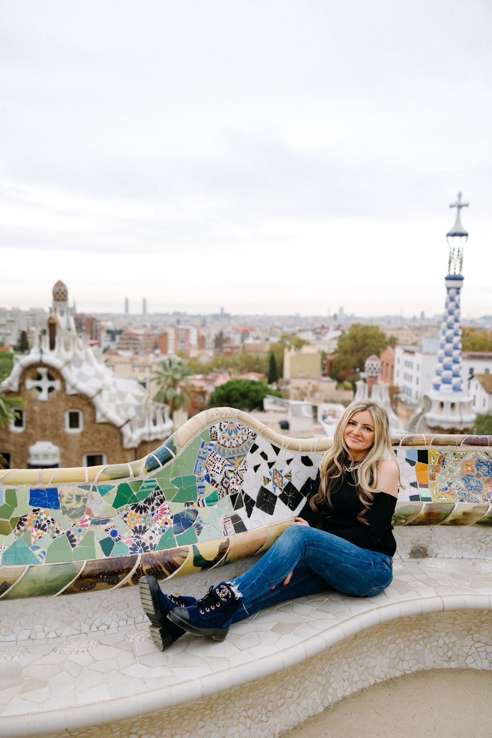 Colorful mosaic benches at Park Guell overlook Barcelona cityscape.
