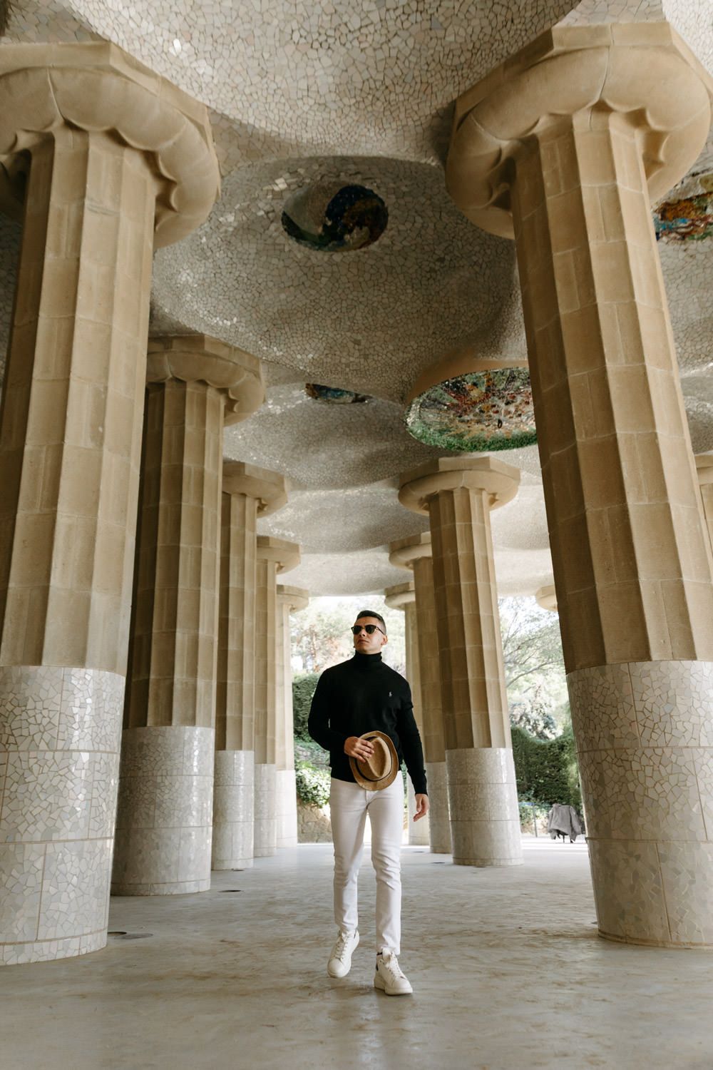 Person stands among towering stone columns in architectural colonnade.