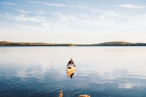 Serene lakeside scene with calm waters and rolling hills in the background.