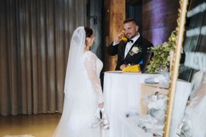 Wedding reception setup in rustic venue with wooden beams and warm lighting.