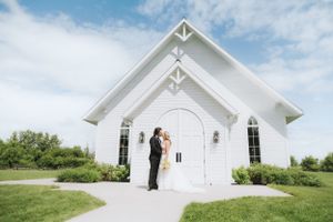 White chapel wedding venue with green landscaping under blue skies.
