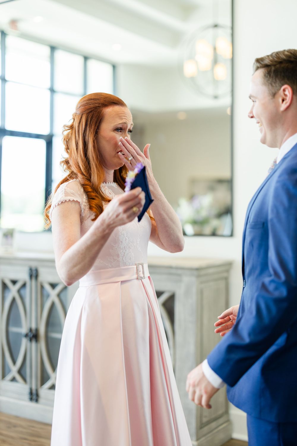 Candid moment between two people in formal attire sharing an emotional reaction during a special occasion.