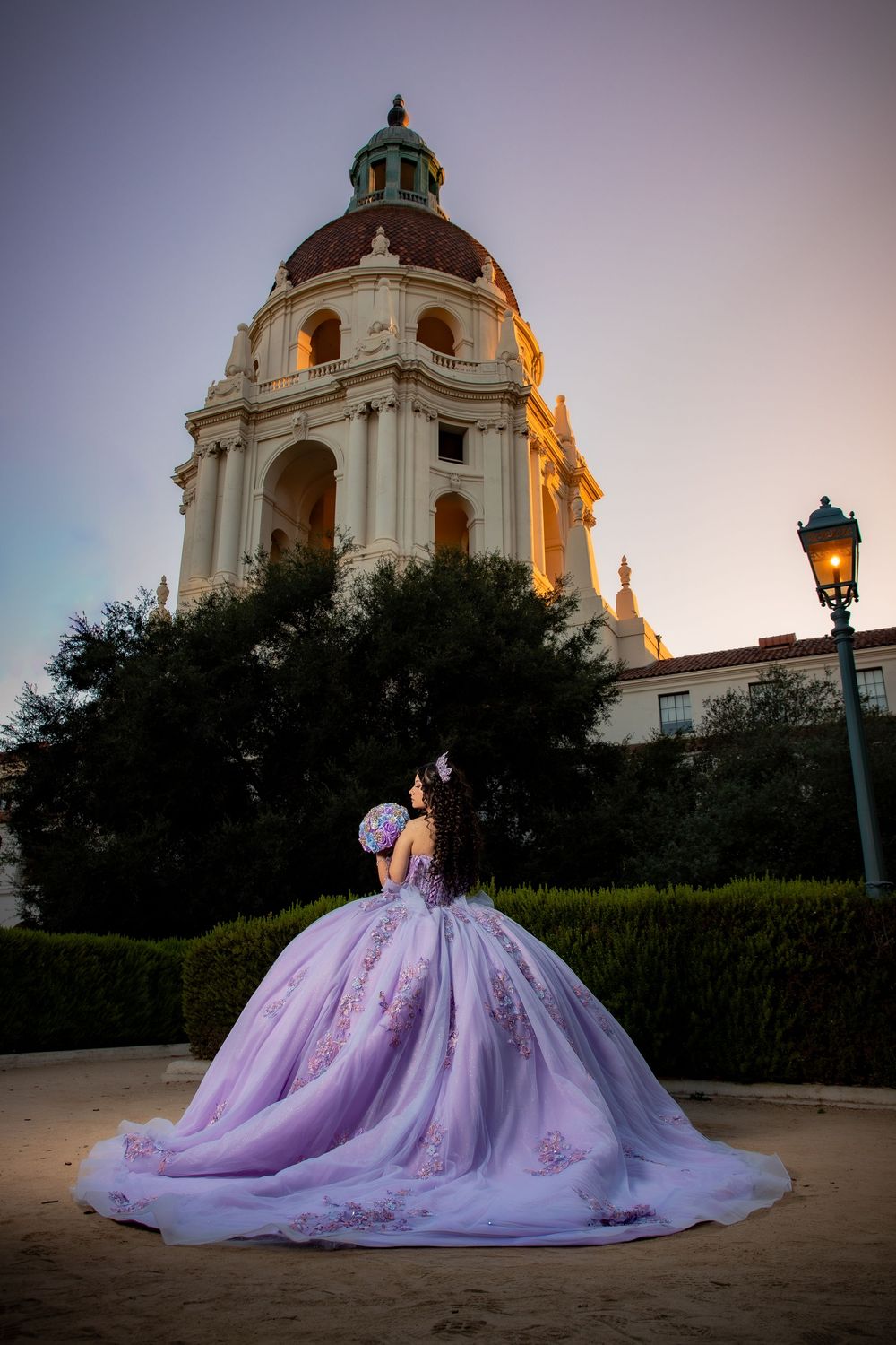 Woman in lavender quinceañera ball gown poses in front of Pasadena City Hall at sunset.