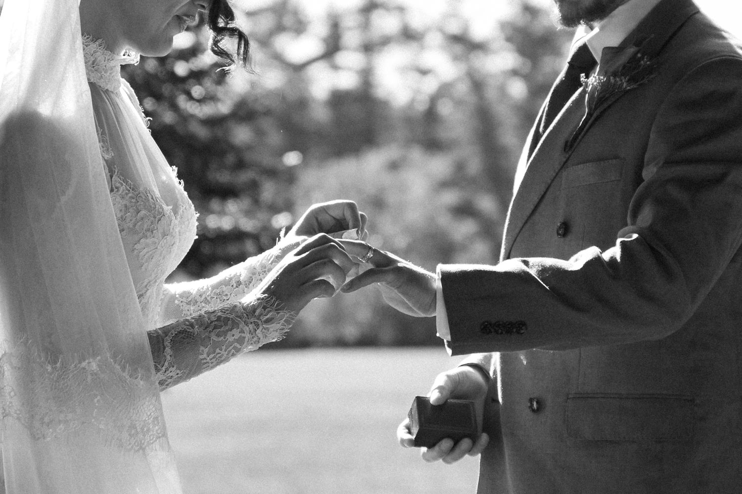 A couple shares a romantic moment during their outdoor wedding ceremony in black and white photography.