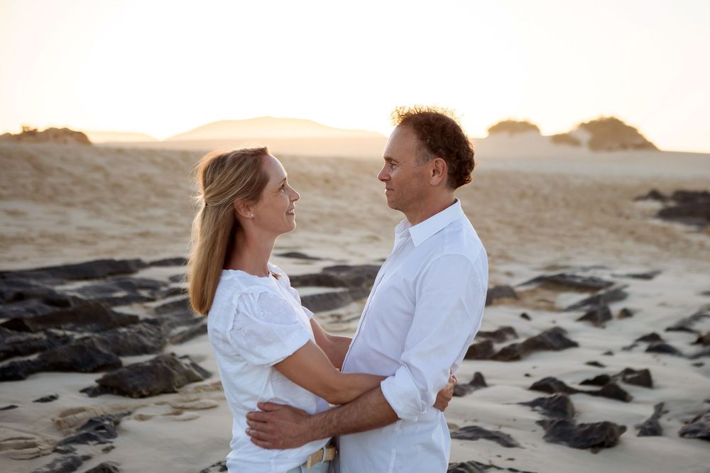 Couple in white shirts facing each other at sunset in the Corralejo dunes - Natural Fuerteventura portraits