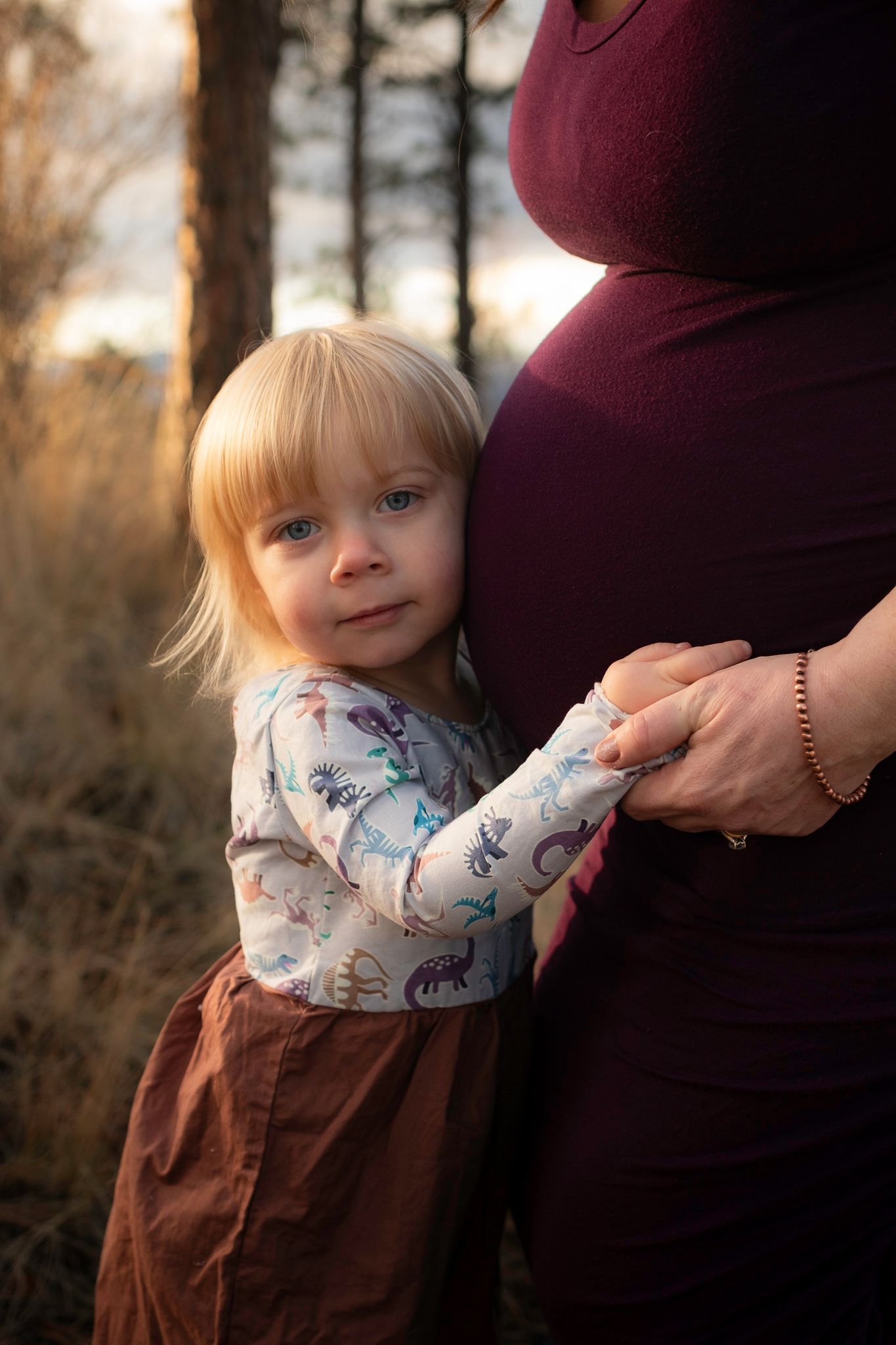 Maternity photo sequence showing small child hugging pregnant woman in burgundy dress outdoors at sunset.