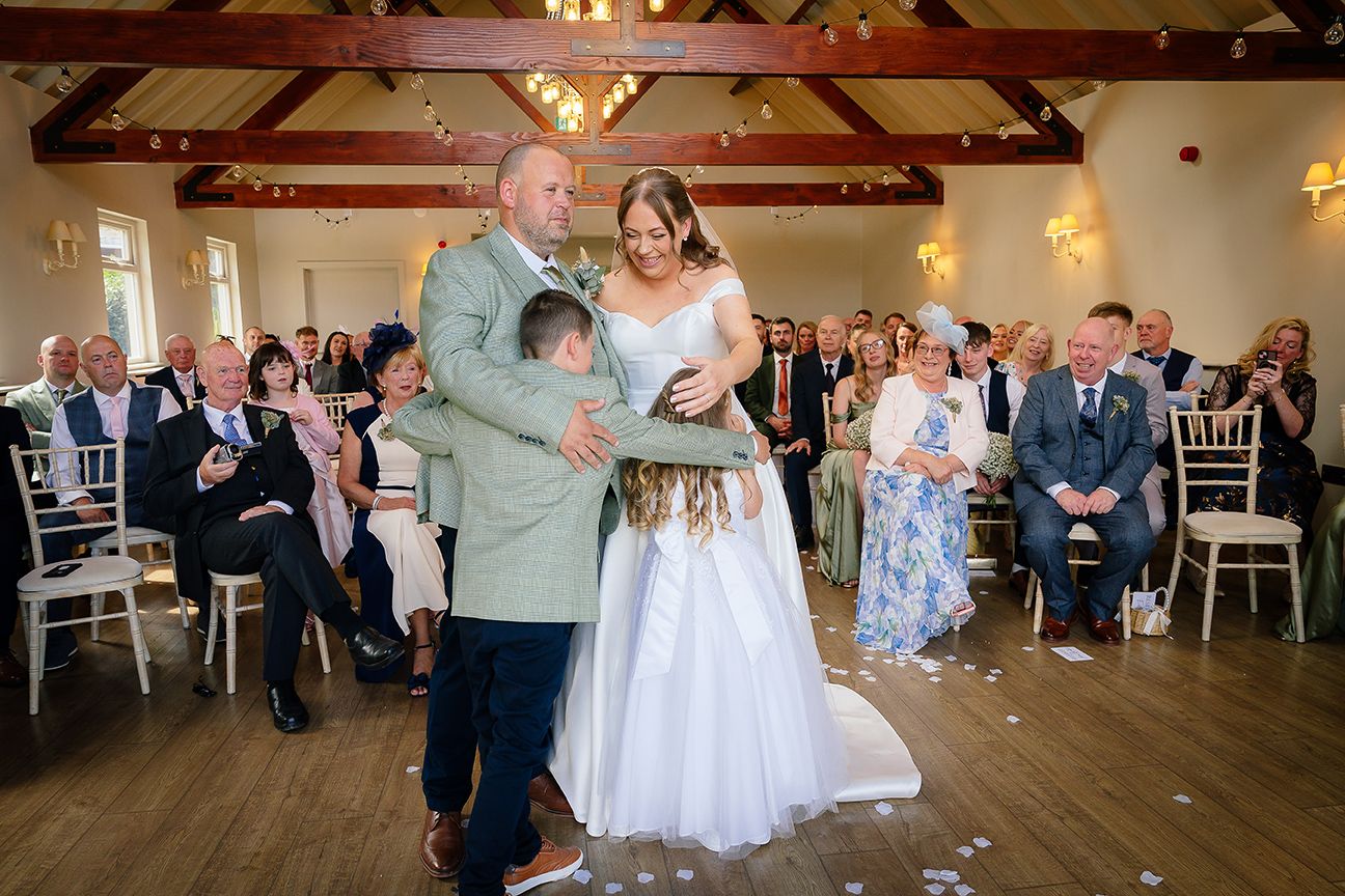 Wedding reception celebration with guests dancing and socializing in rustic wood-beamed venue.