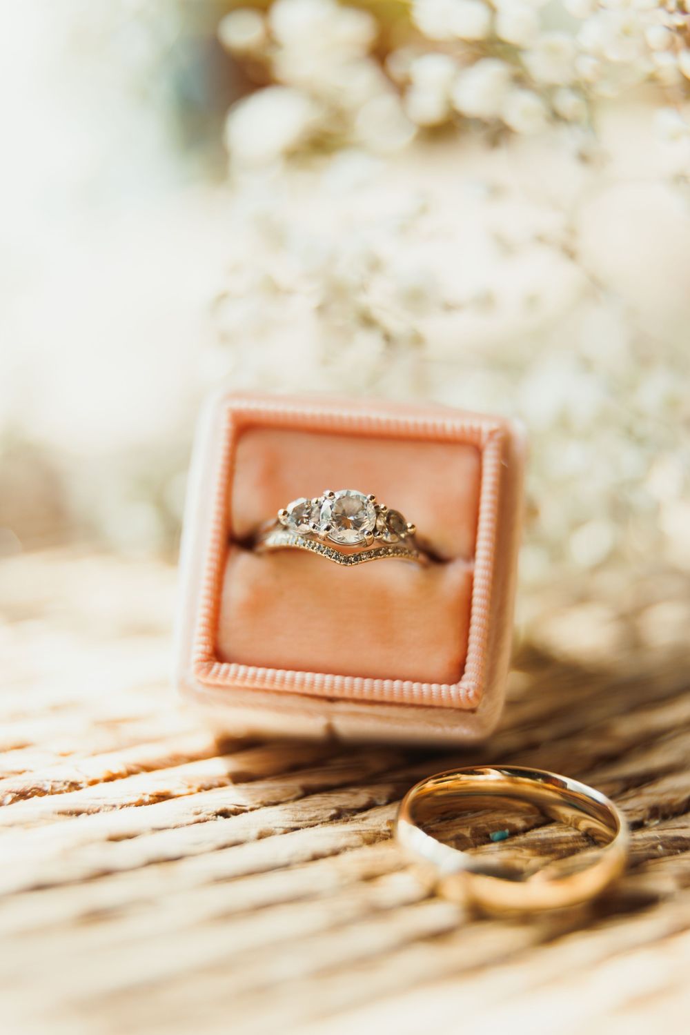 Wedding rings arranged artistically in coral-colored velvet boxes on a textured surface.