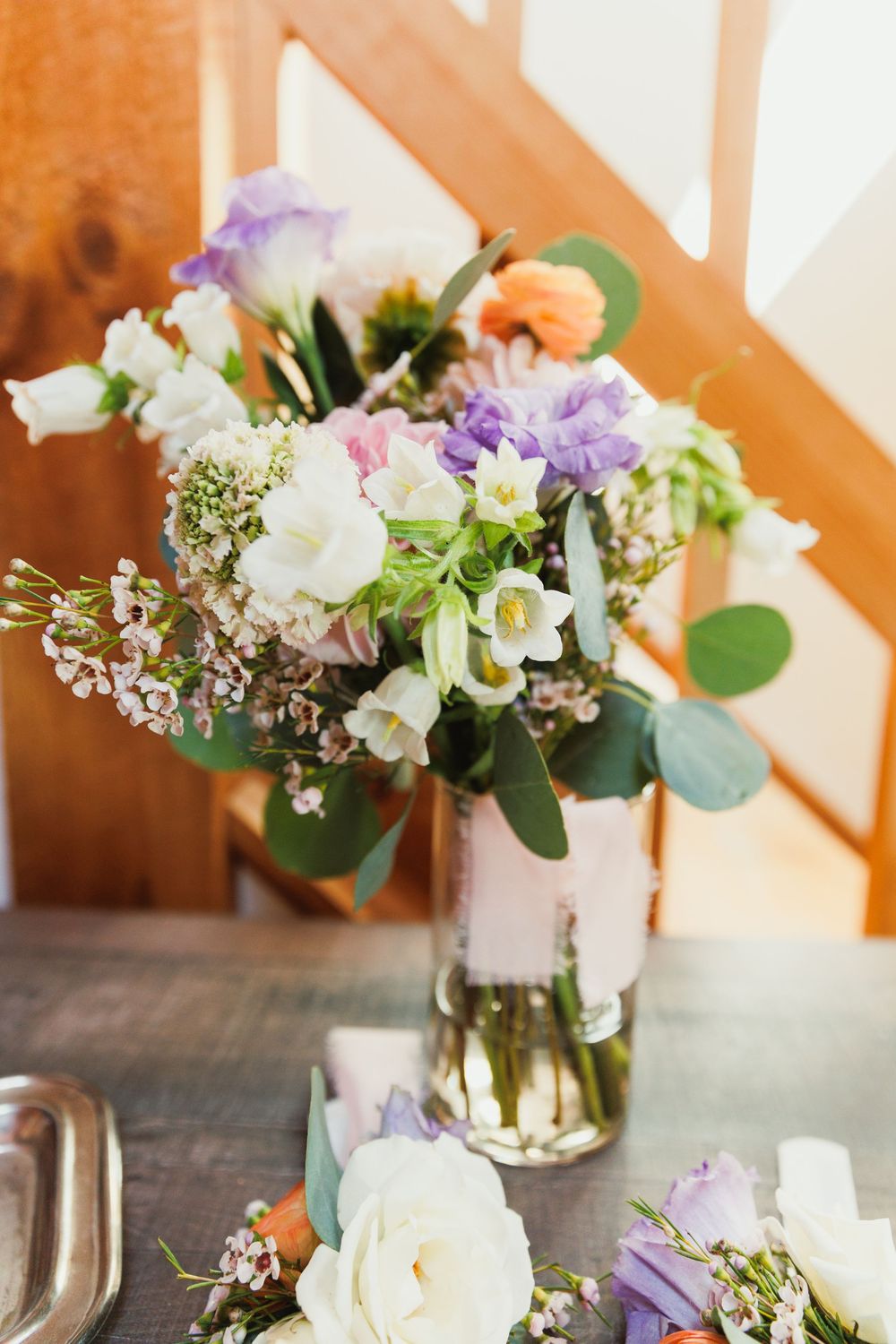 Elegant floral centerpieces with white and purple blooms in glass vases on wooden tables.