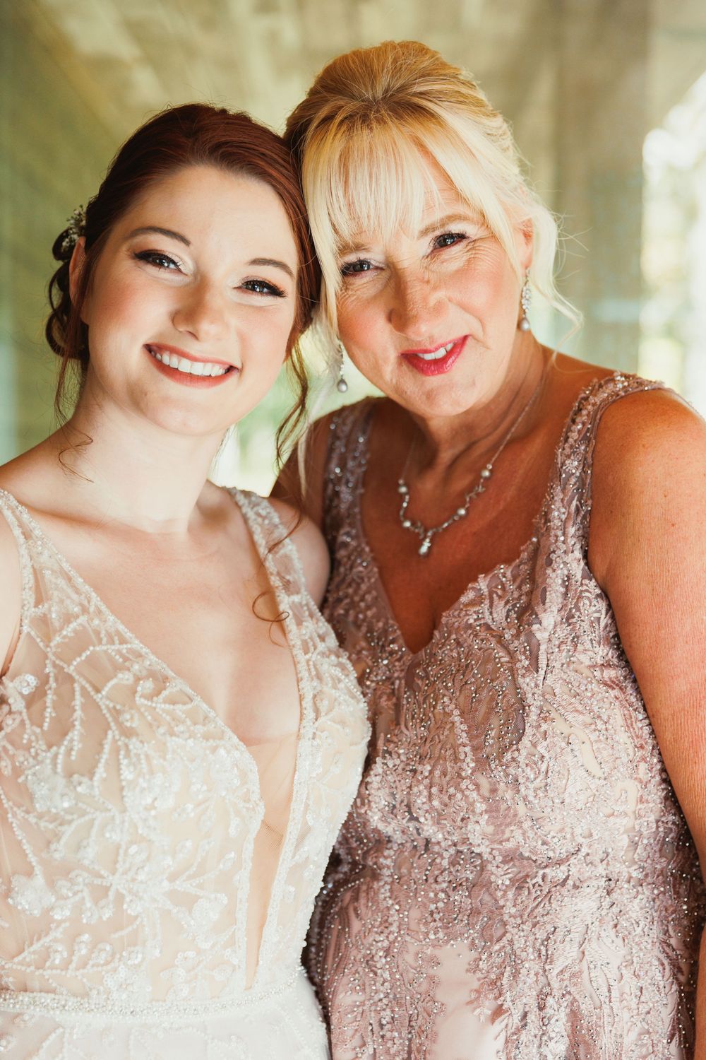 Two people share a warm embrace while wearing elegant formal dresses in complementary shades.