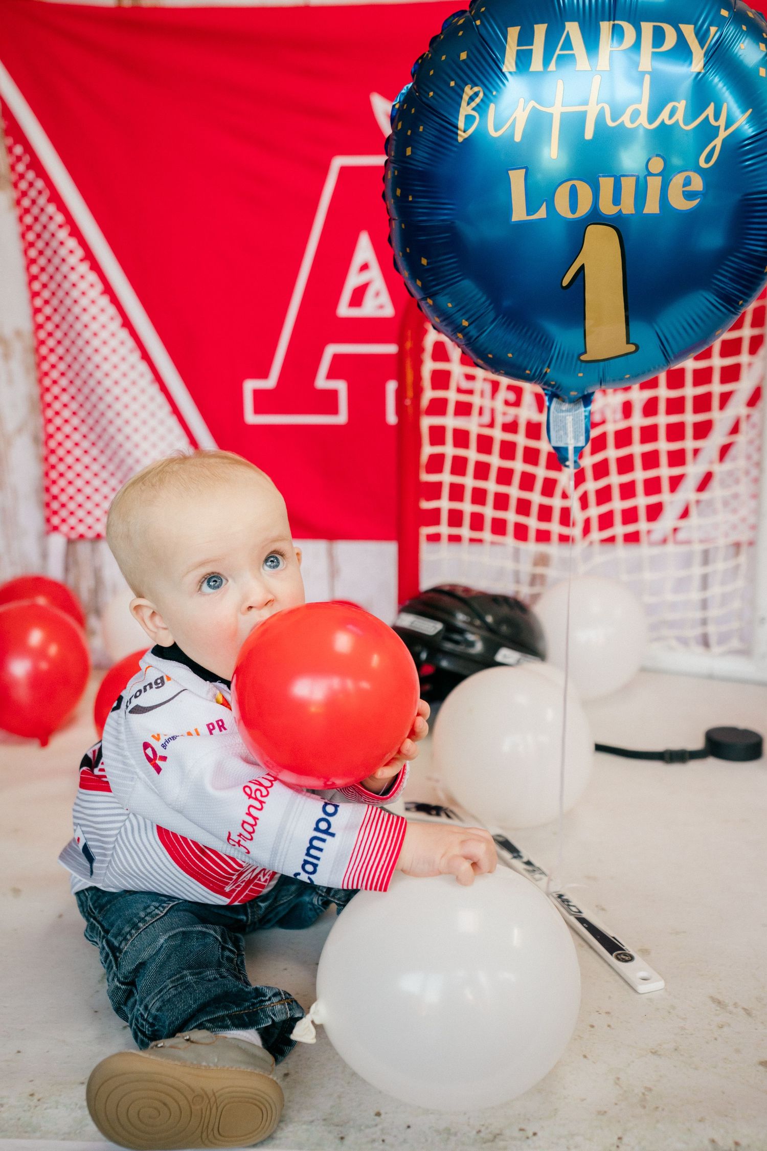 Lifestyle family photography of a one year old baby sitting with balloons during a relaxed first birthday photoshoot