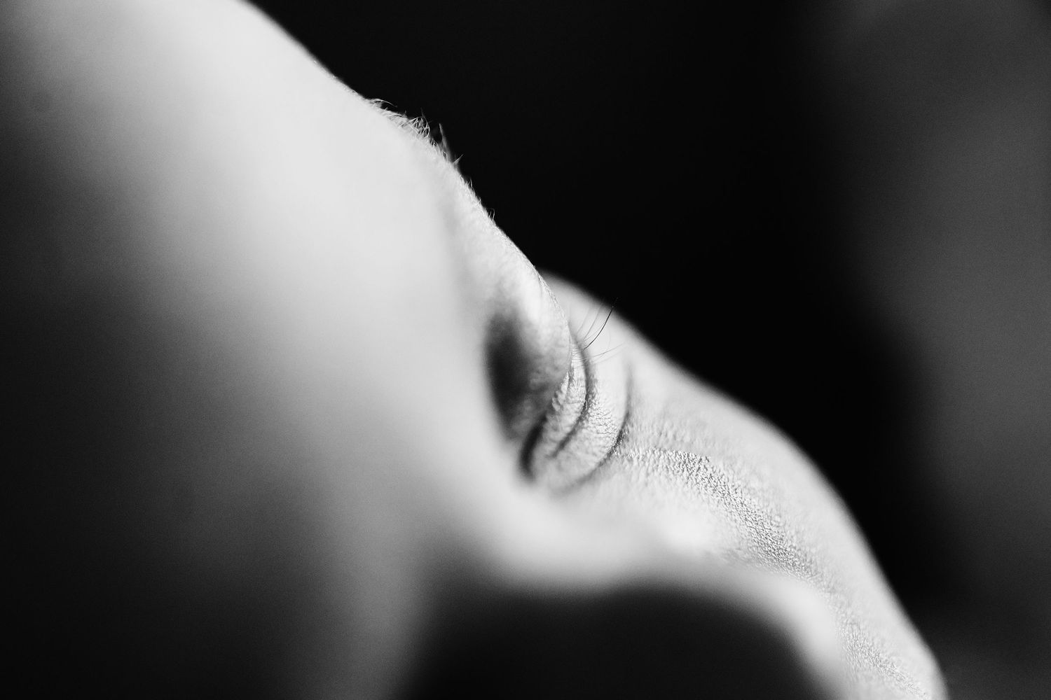 Black and white macro photograph of abstract human body curves and shadows creating artistic composition.