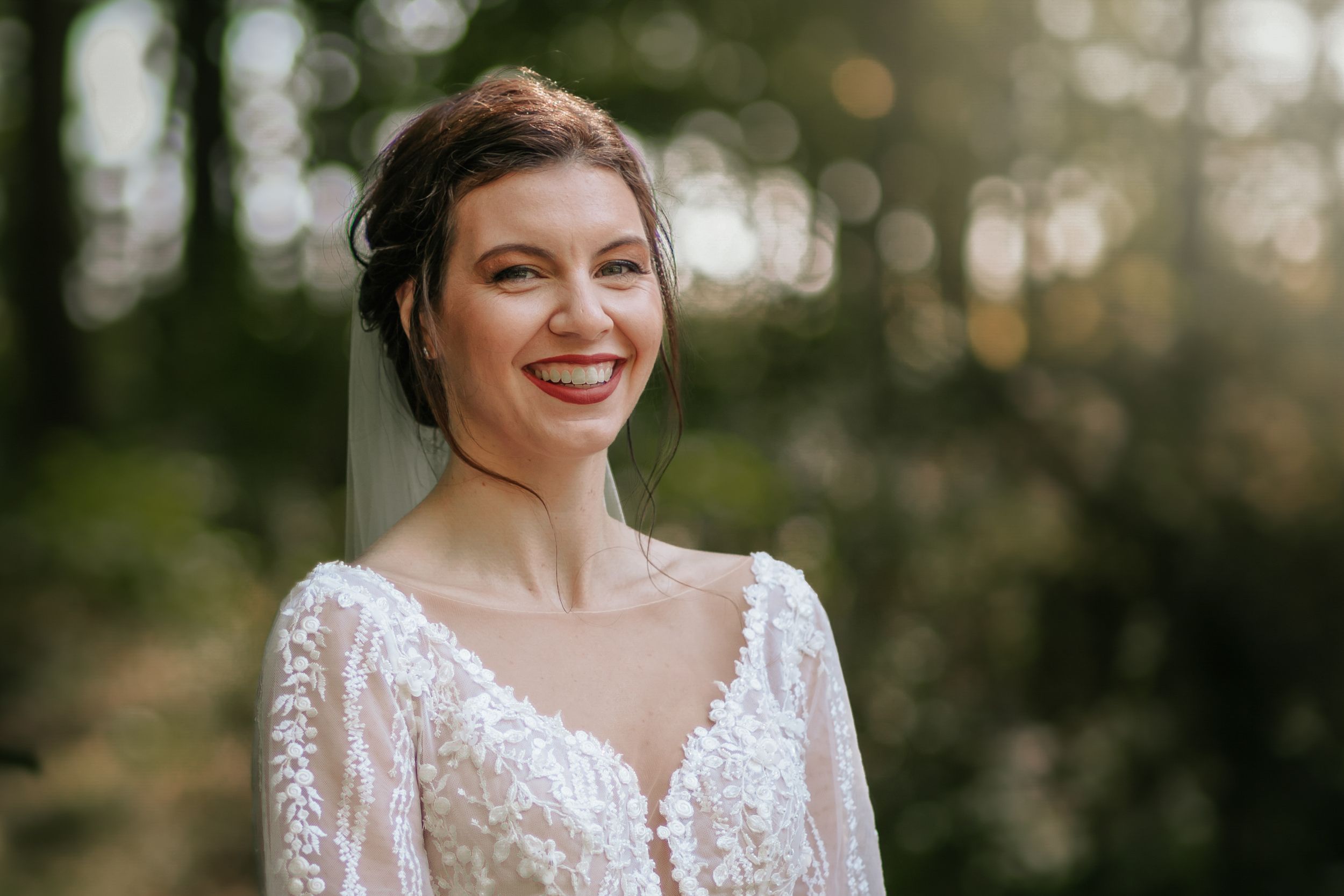 Ethereal bridal portrait in a sunlit forest setting.