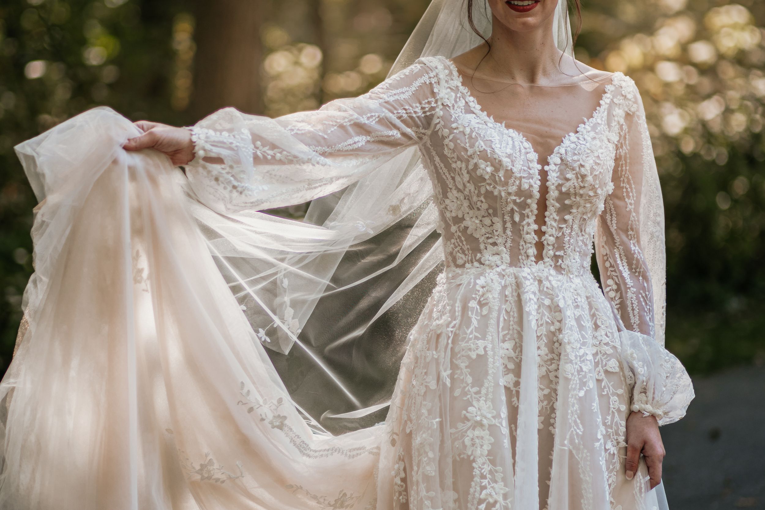 Flowing white wedding dress with lace details captured in natural outdoor lighting.