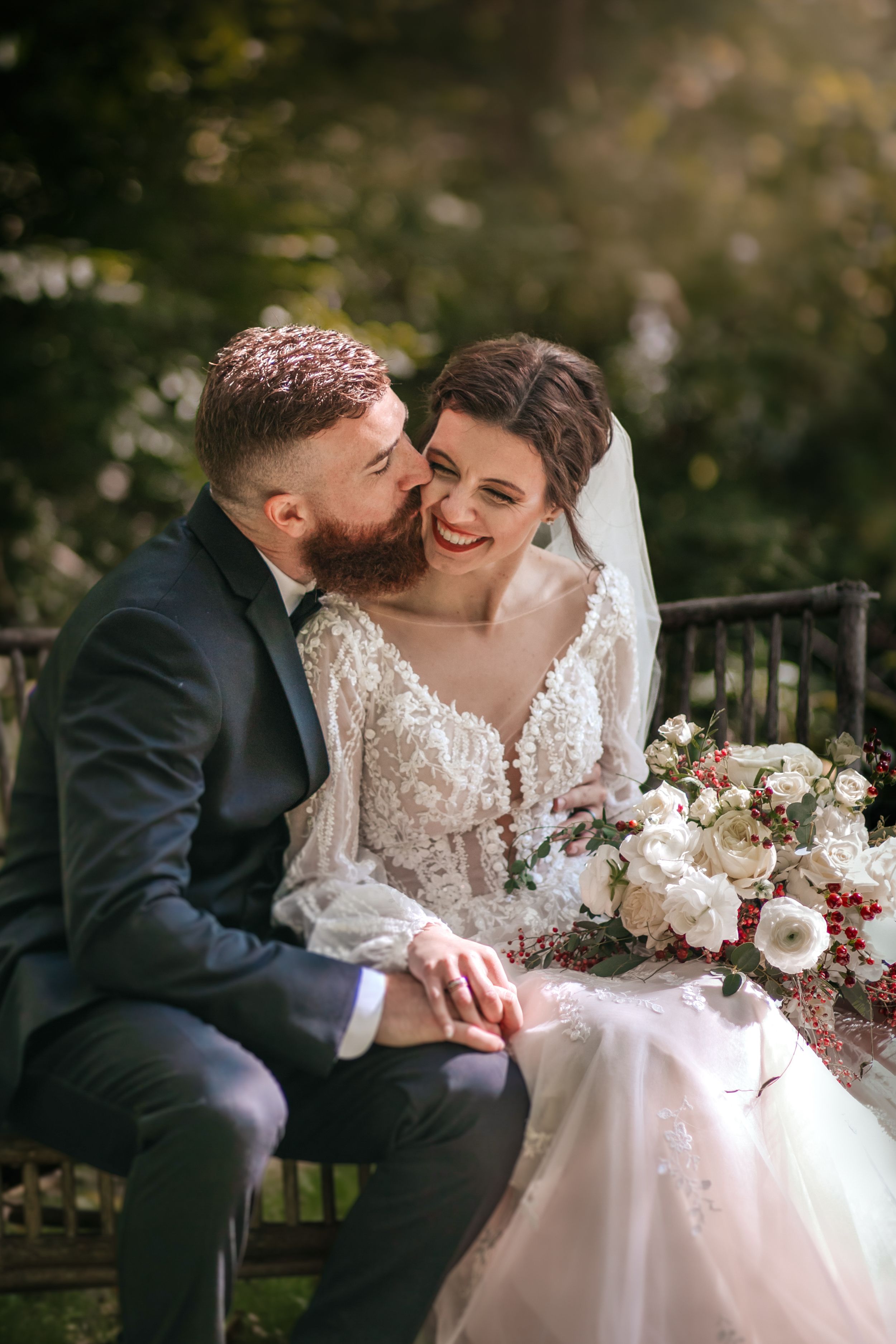 Intimate wedding couple shares tender moment on rustic bench outdoors.