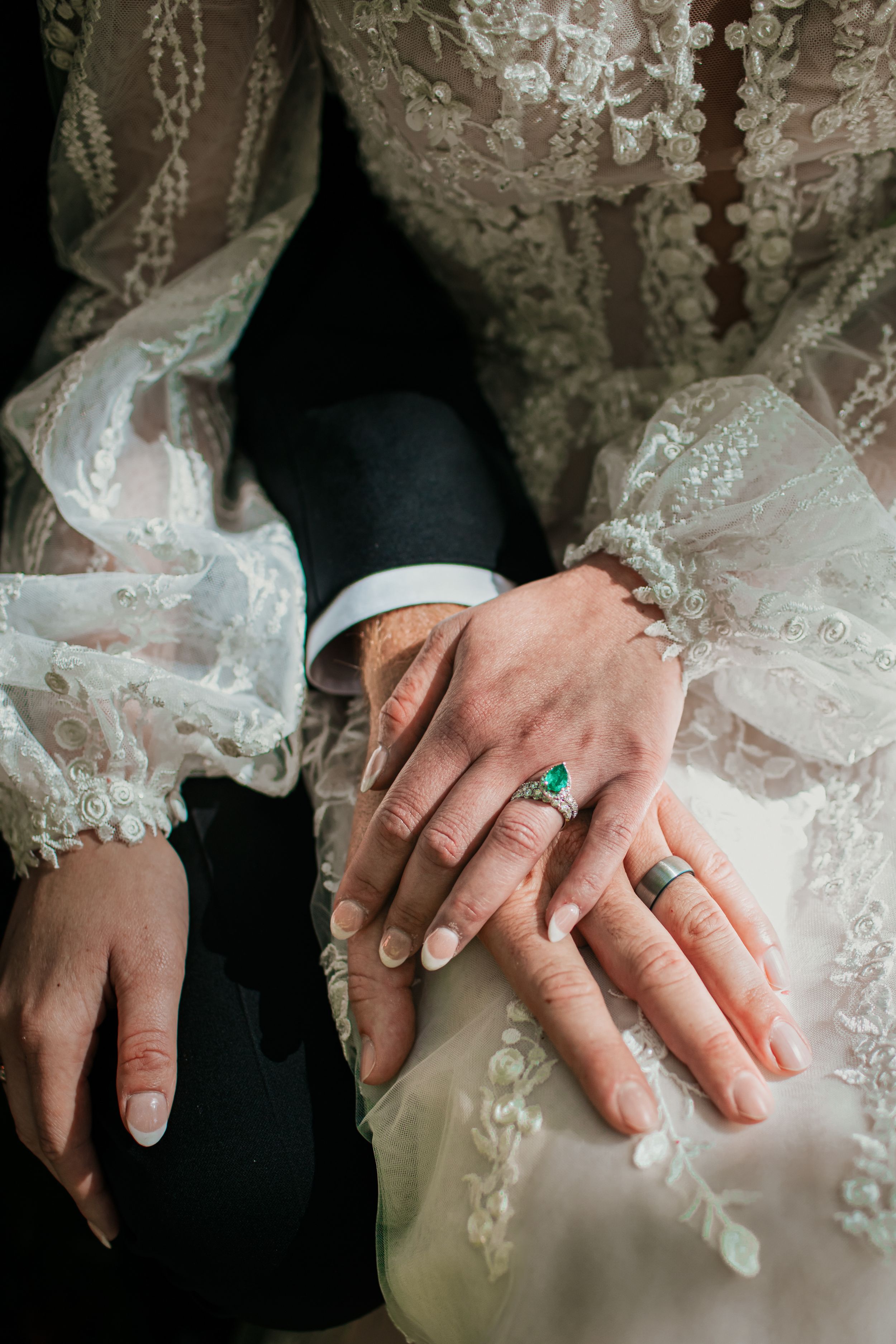 Close-up of wedding rings and lace details on bride's dress.
