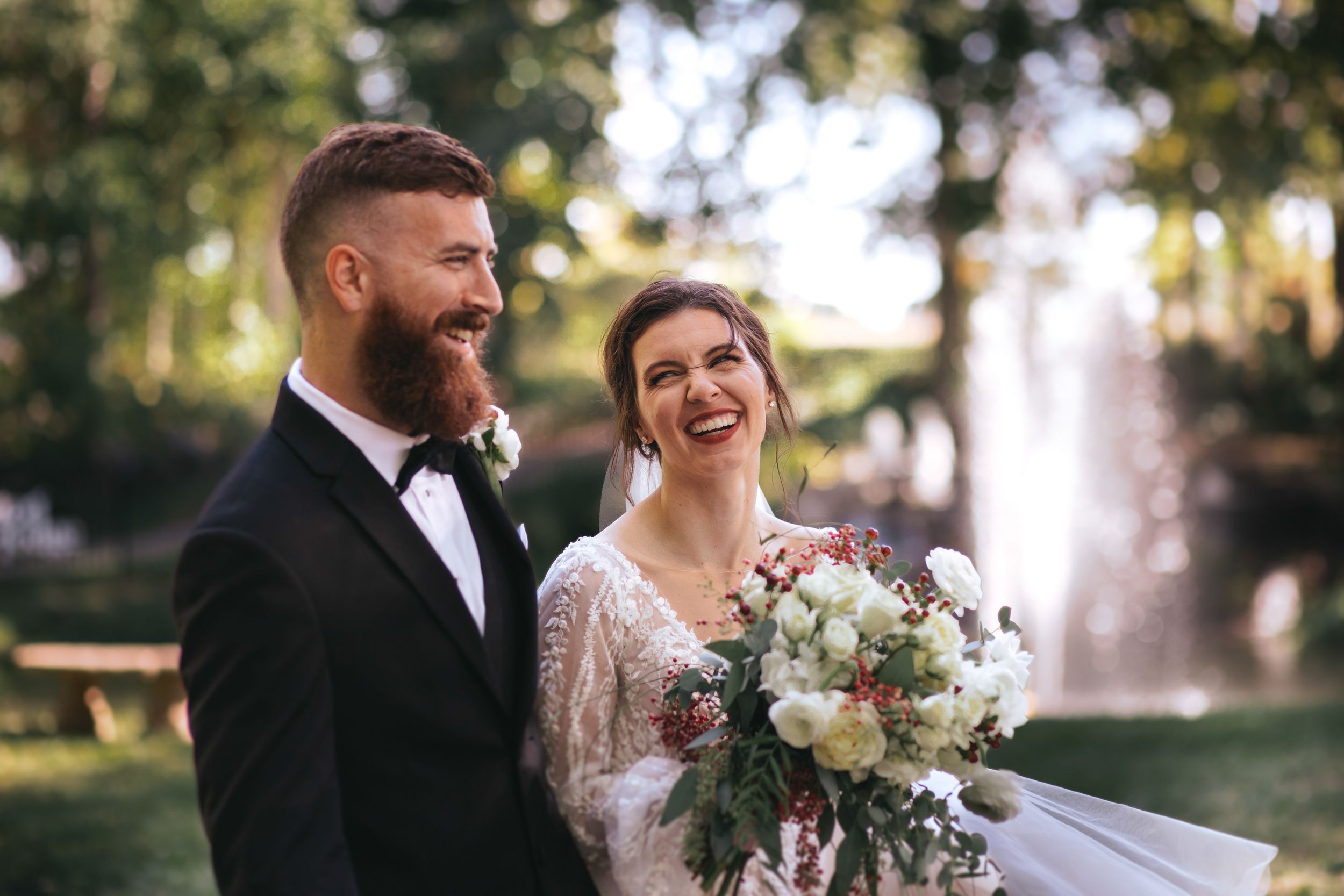 A romantic wedding couple shares an intimate moment outdoors during golden hour sunset.
