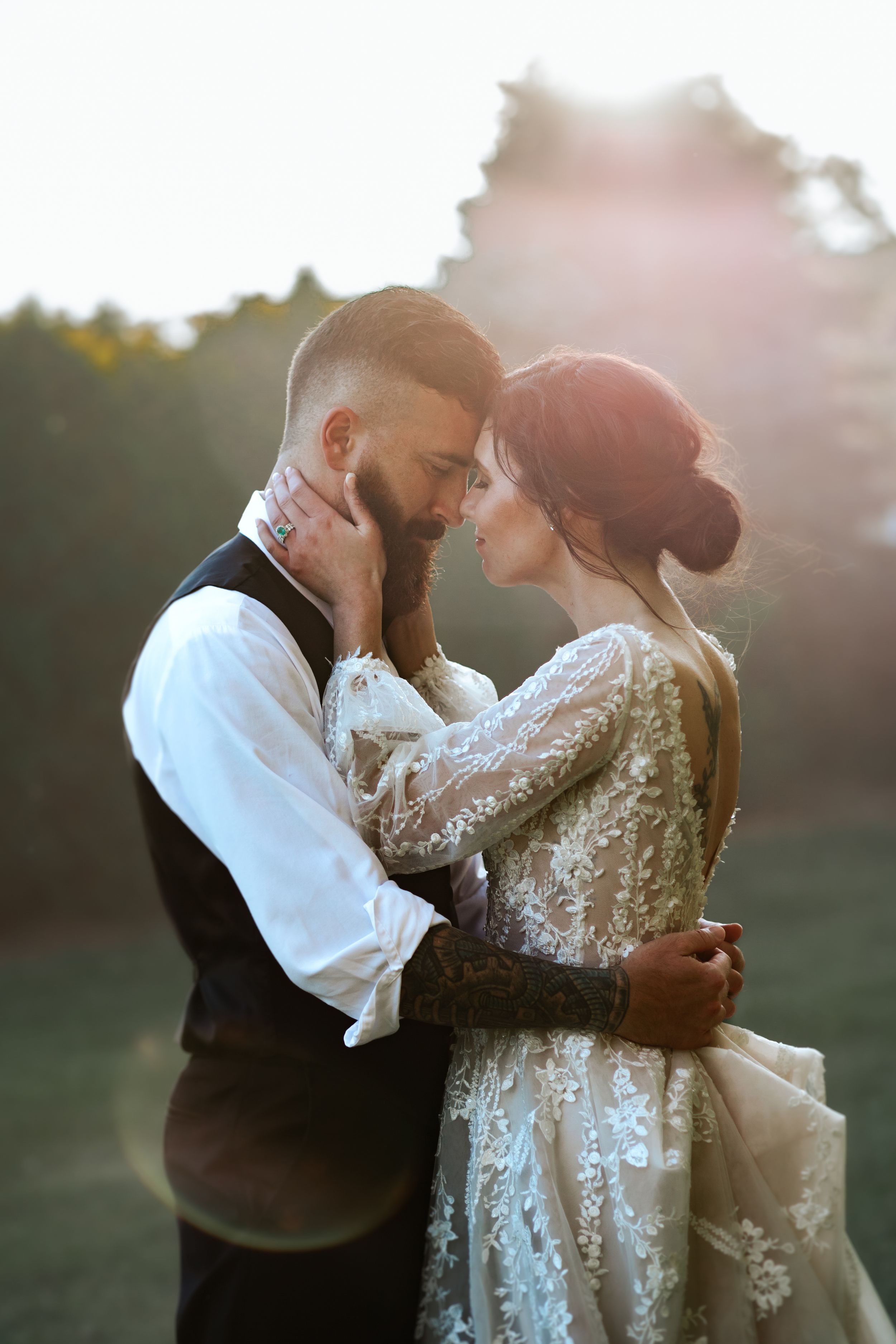 Newlyweds embrace in a sunlit field during their romantic sunset wedding photoshoot.