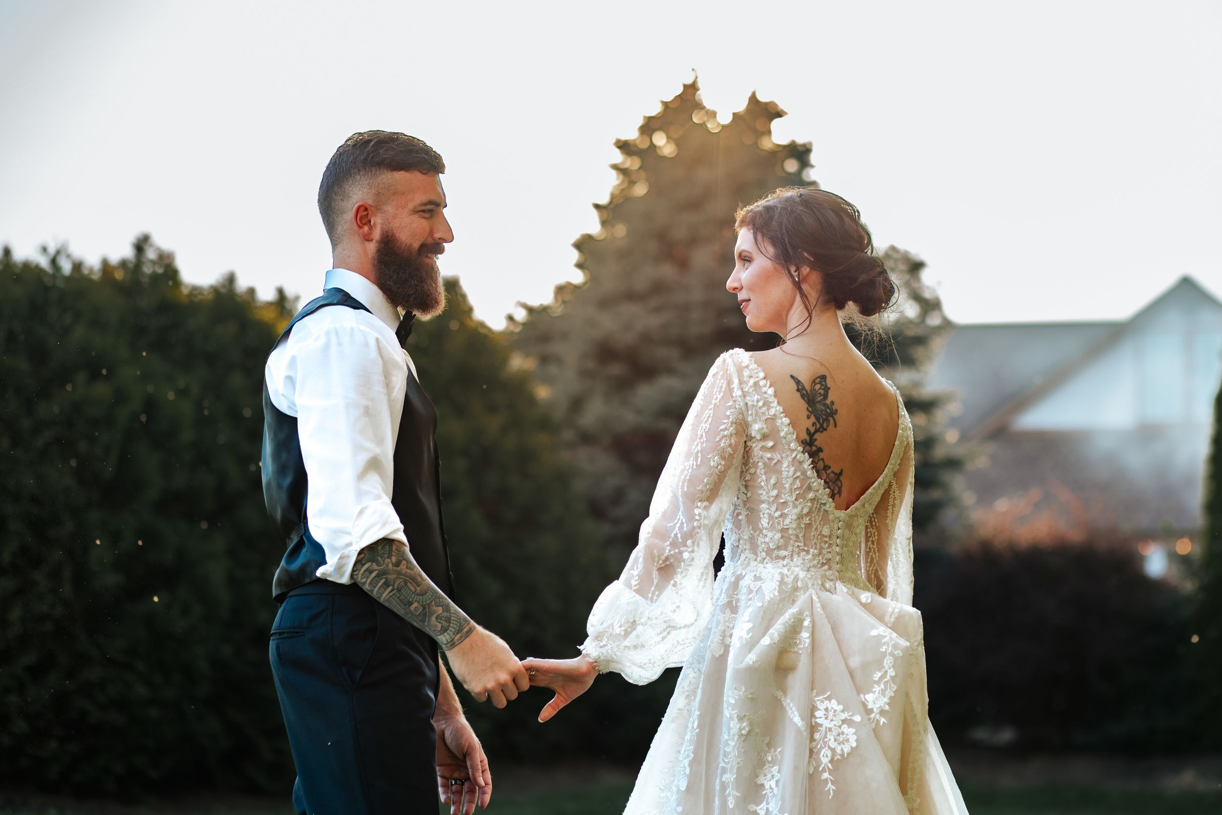 Bride in lace gown and groom share a romantic dance outdoors.