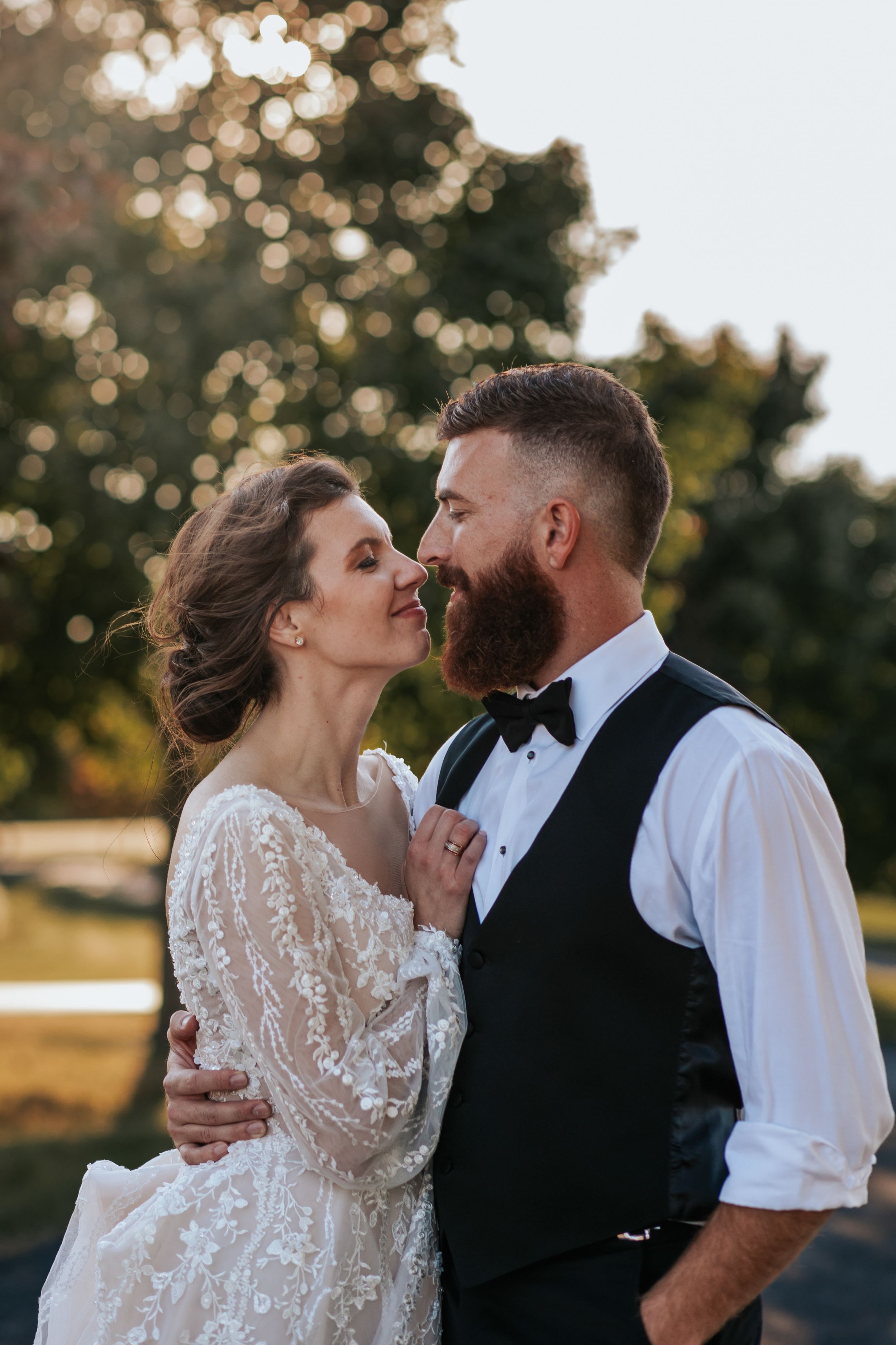 Intimate wedding portrait in golden hour light with couple in formal attire sharing tender moment.