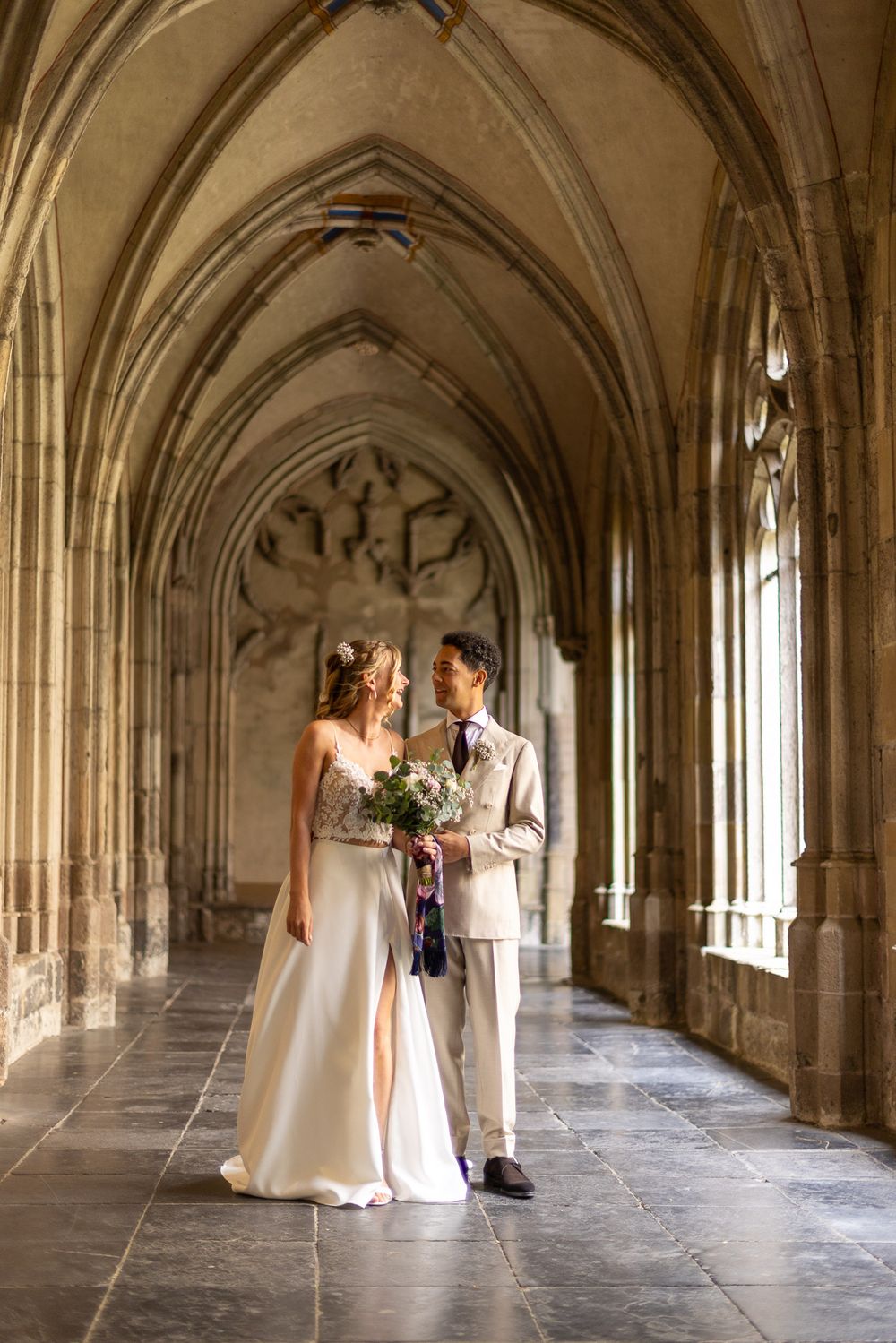 Bruidspaar wordt prachtig verlicht door binnenschijnende zonlichtstralen in het klassieke Pandhof van de Dom - Utrecht - MaxFotos