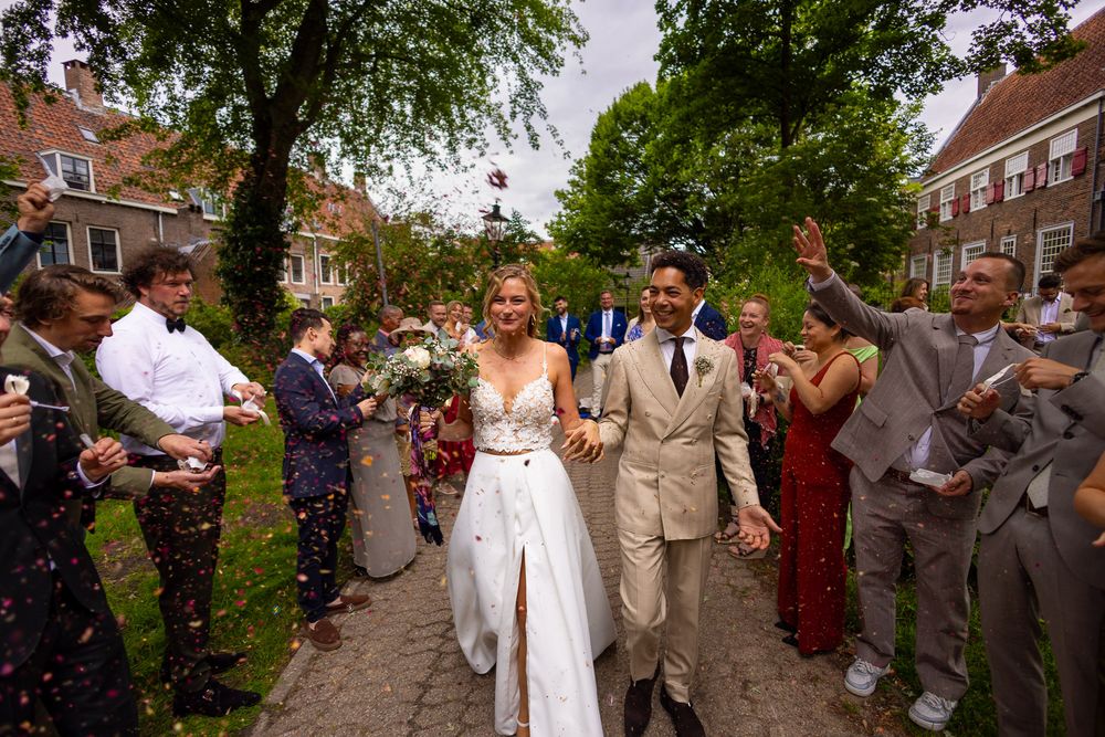 Lachend bruidspaar loopt door erehaag met confetti - documentaire trouwfotografie in de stad - Utrecht - MaxFotos