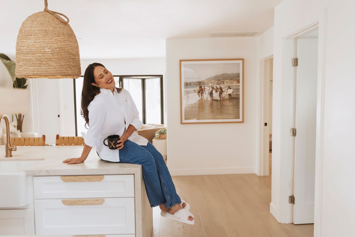 A woman holds a coffee cup and laughs in a light and bright San Diego home