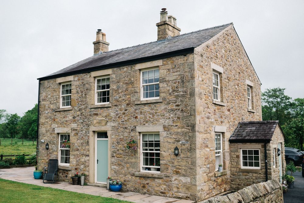 Traditional stone farmhouse exterior with multiple windows and rustic architecture.