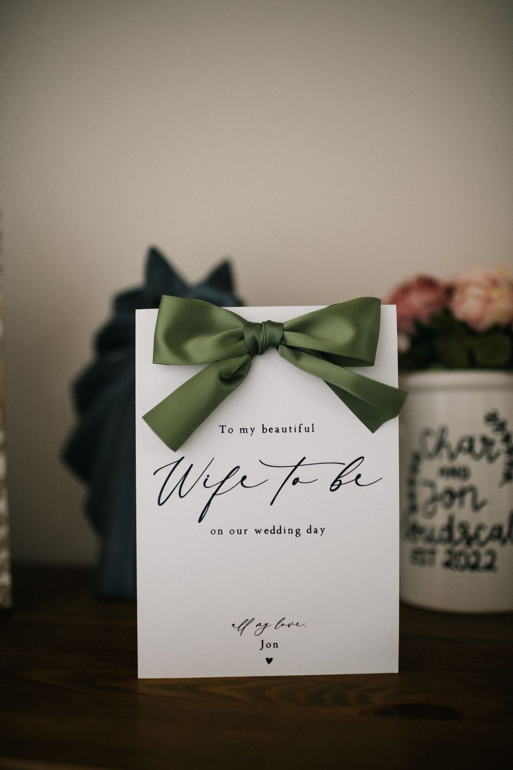 Wedding card with green bow and 'Wife to be' text on white paper.