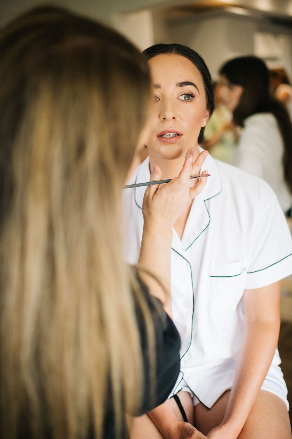 A makeup application session in progress showing an artist in a white uniform working on a client.