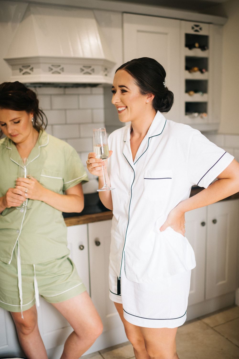 Wedding morning preparations showing women in casual and formal attire in modern white kitchen.