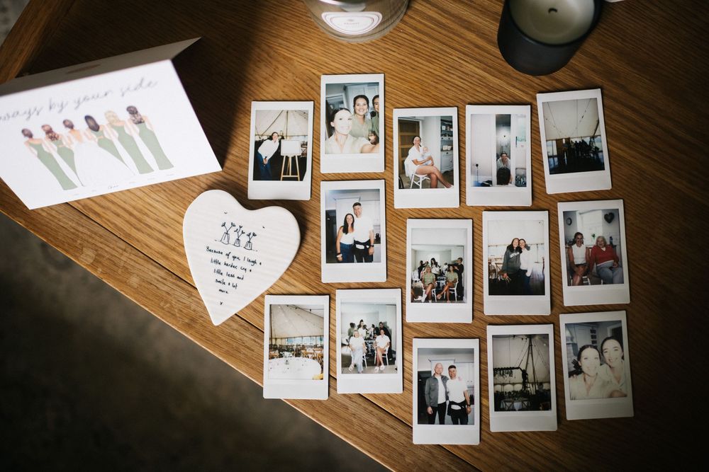 Collection of polaroid wedding photos and a heart-shaped note displayed on a wooden table.