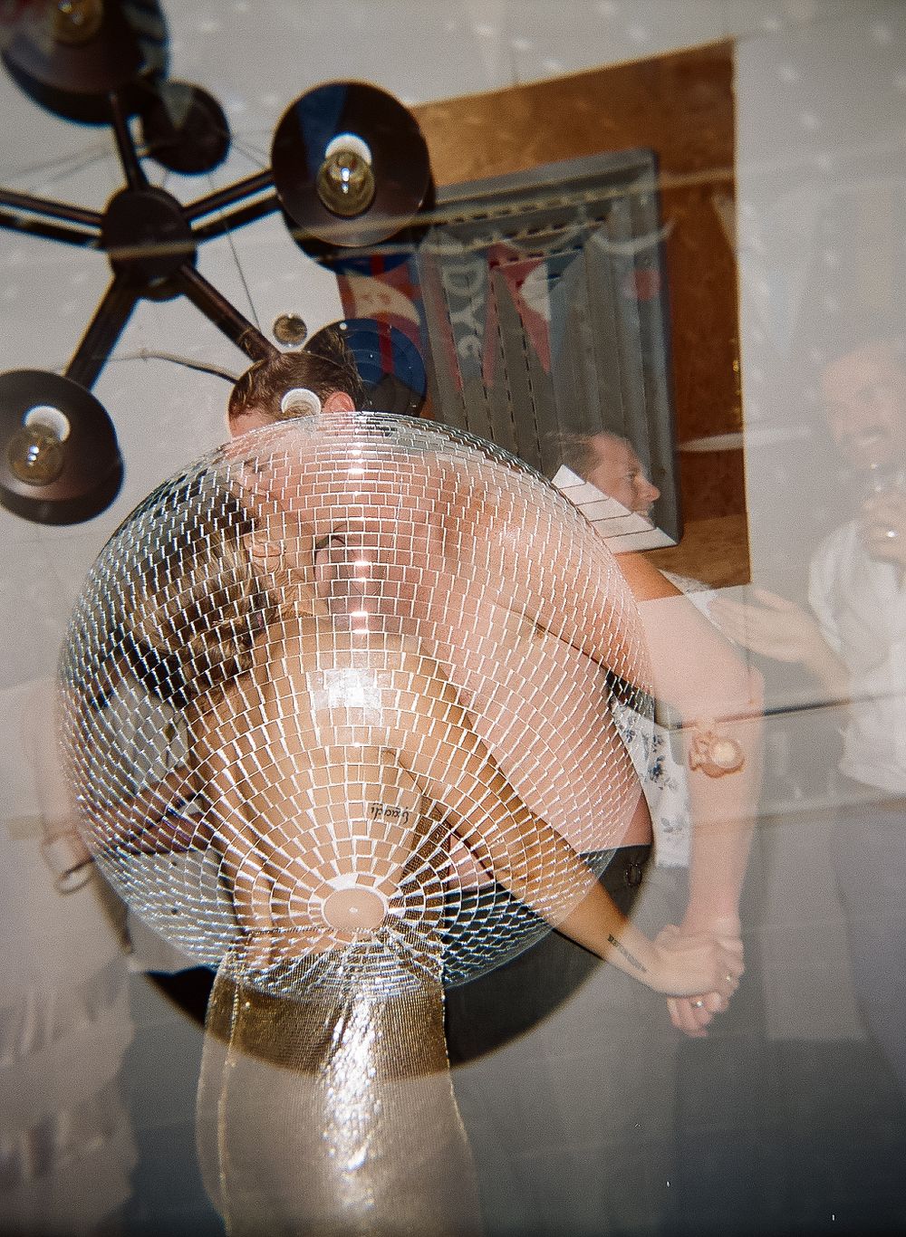 Large disco ball reflects light in a dimly lit party venue.