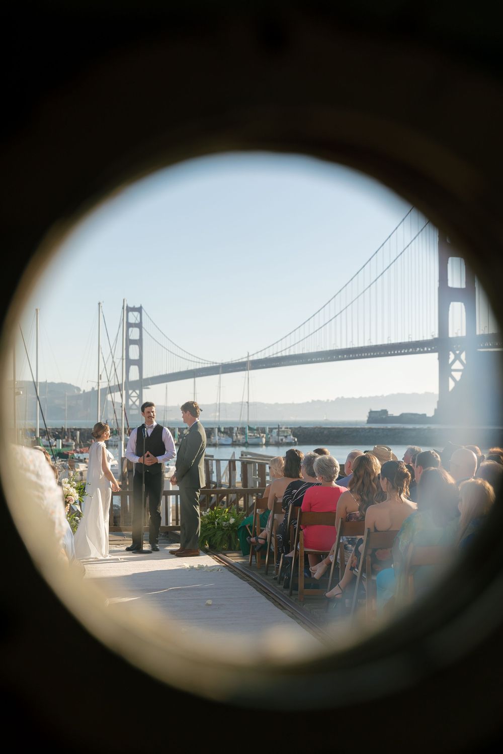 Wedding ceremony overlooking the Golden Gate Bridge through a circular frame.