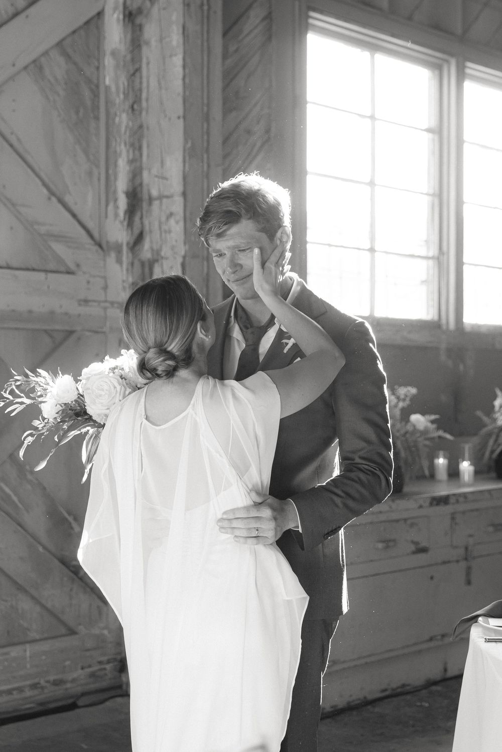 Black and white photos of a couple dancing in a rustic venue with natural window light.