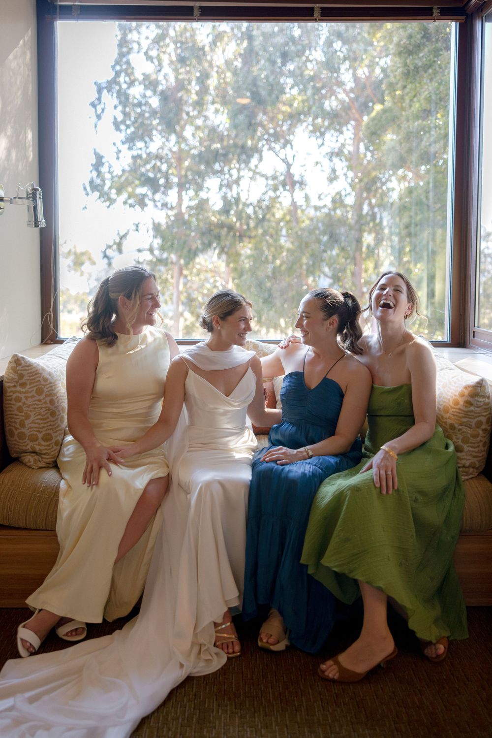 Wedding party relaxing and laughing together on a couch in formal dresses.