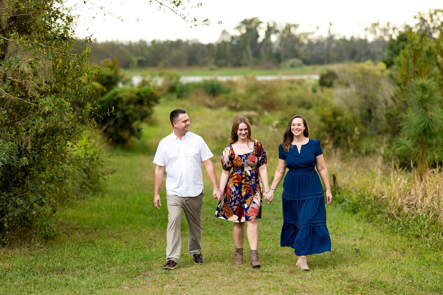 A family walking together through a lush green field on a sunny day, shown in multiple candid poses.