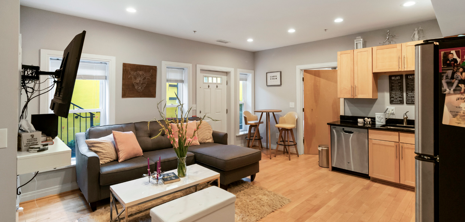 Open concept living room and kitchen with hardwood floors and modern grey sectional sofa.