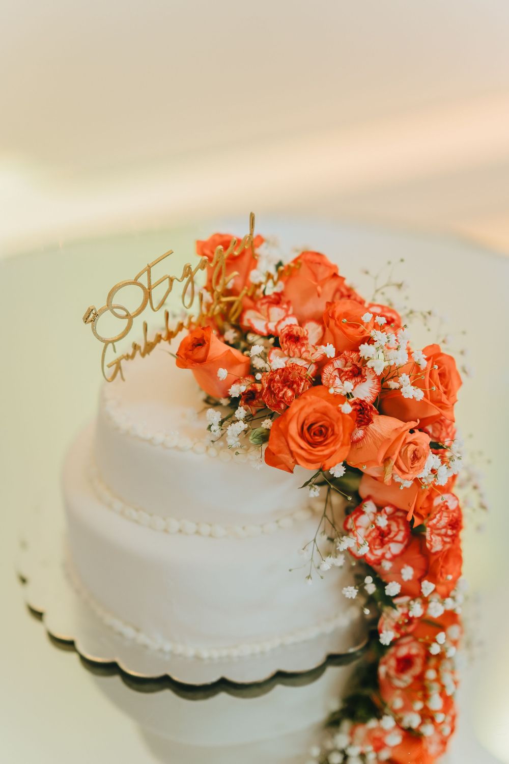 White wedding cake decorated with coral orange roses and baby's breath flowers.
