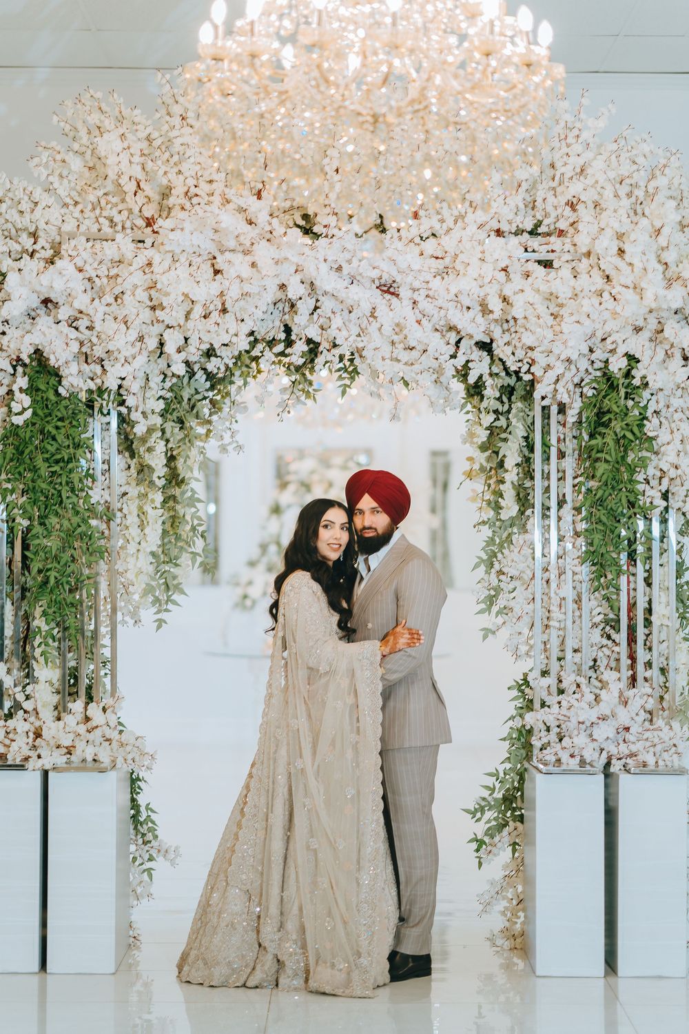Elegant wedding ceremony setup with white cherry blossom arches and greenery creating a romantic backdrop.