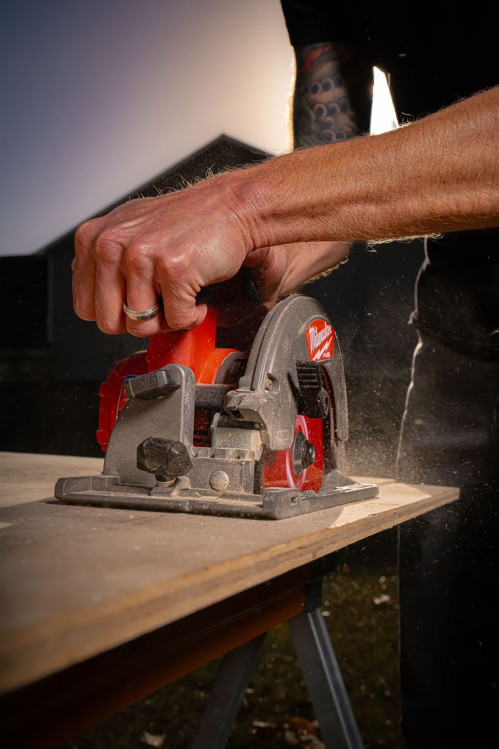 A circular saw cutting through a wooden plank on a workbench, creating sawdust during home improvement work.