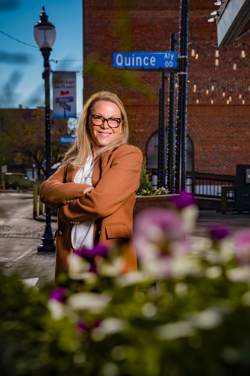 A series of urban portraits against a brick wall with blurred flowers in the foreground and a street sign visible.