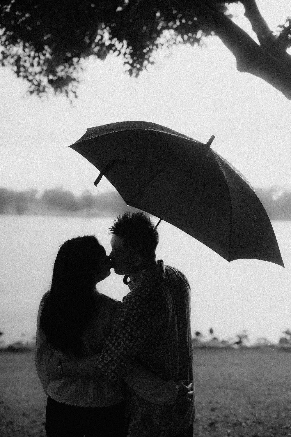 A romantic silhouette of a couple sharing an umbrella in black and white photography.