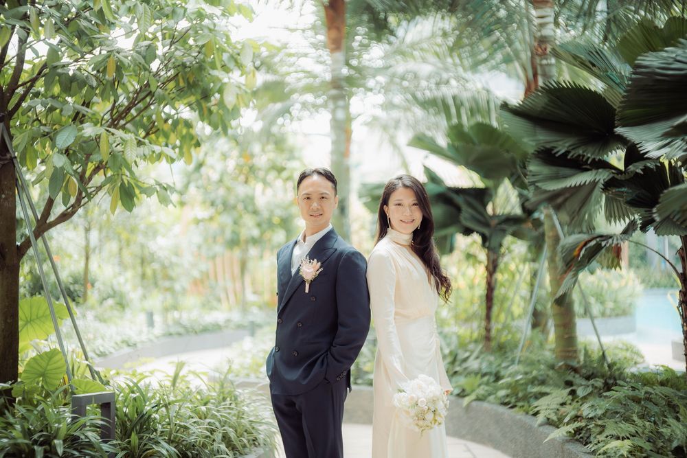 Wedding couple posing in a lush tropical garden setting with natural greenery.
